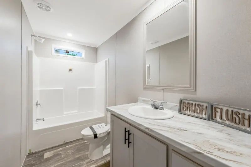 A bathroom with a sink , toilet , tub and mirror.