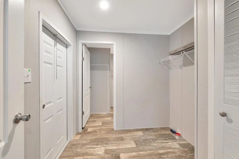 A hallway in a house with white doors and wooden floors leading to a laundry room.