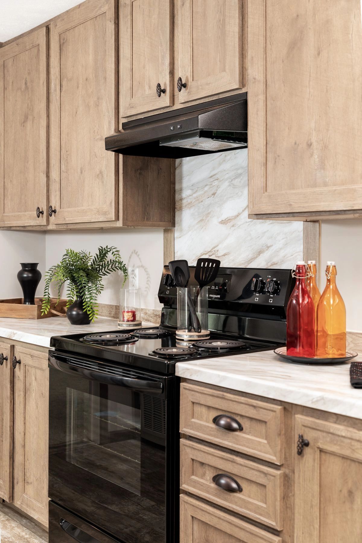A kitchen with wooden cabinets , a black stove and a black oven.