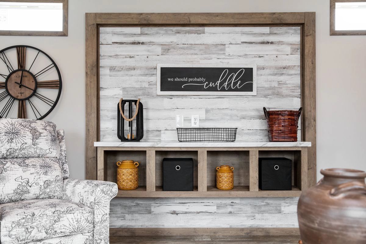 A living room with a clock on the wall , a chair , and a shelf.