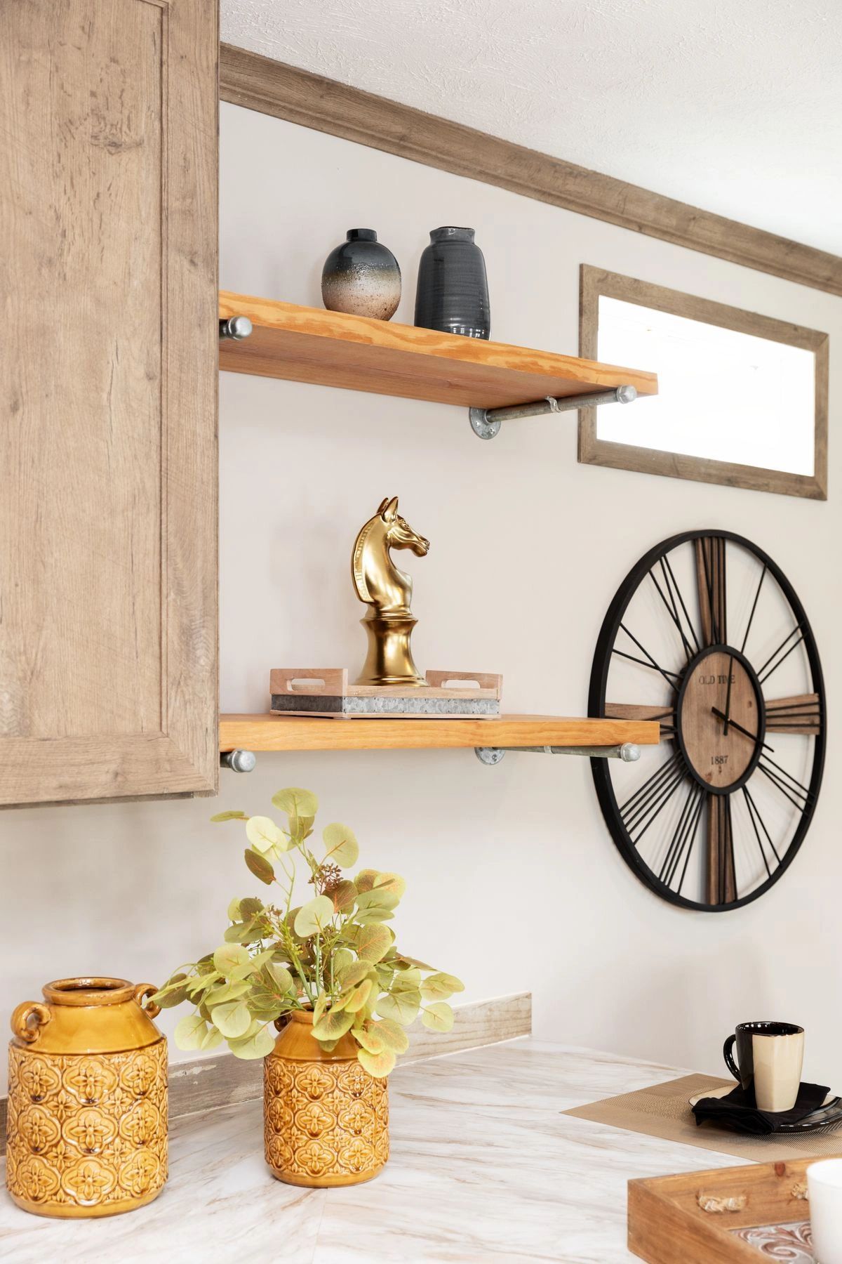 There is a clock on the wall above the shelves in the kitchen.