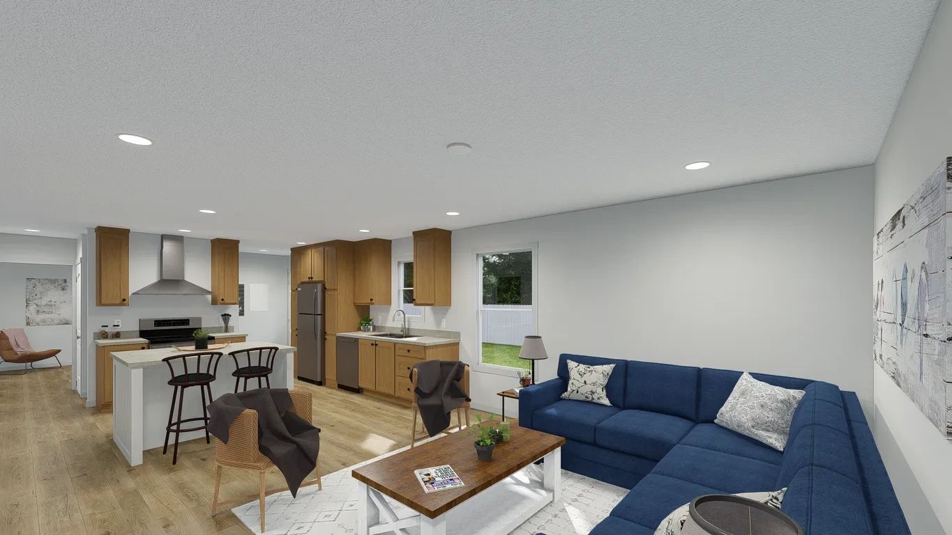 A living room with a blue couch , coffee table , chairs and a kitchen.