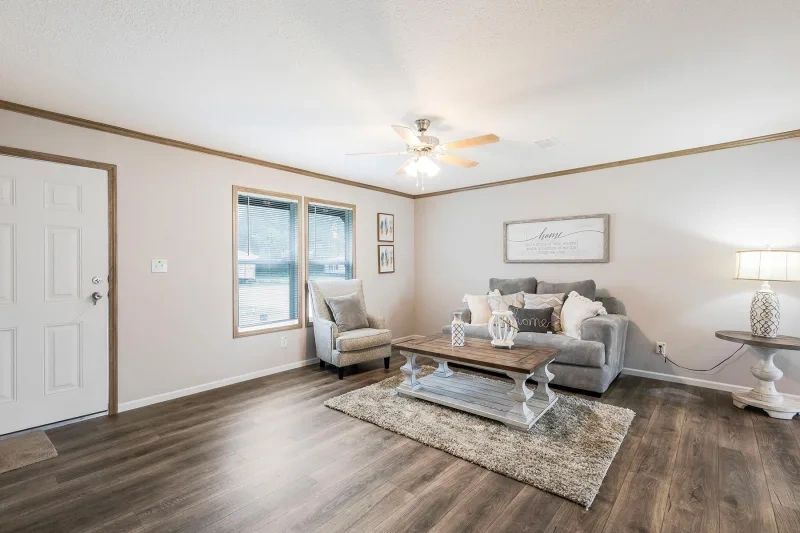 A living room with a couch , chair , coffee table and ceiling fan.
