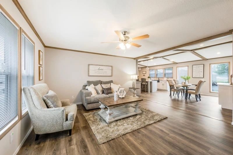 A living room with a couch , chair , coffee table and ceiling fan.