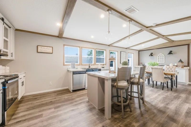 A kitchen and dining room in a mobile home with hardwood floors and stainless steel appliances.