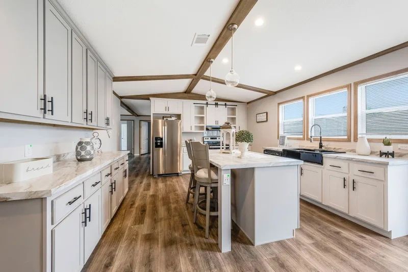 A kitchen in a mobile home with white cabinets and stainless steel appliances.
