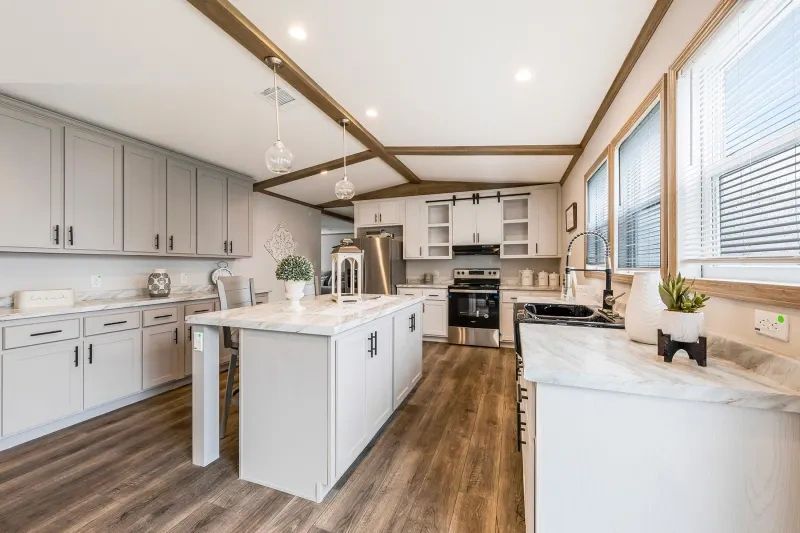 A kitchen in a mobile home with stainless steel appliances and white cabinets.