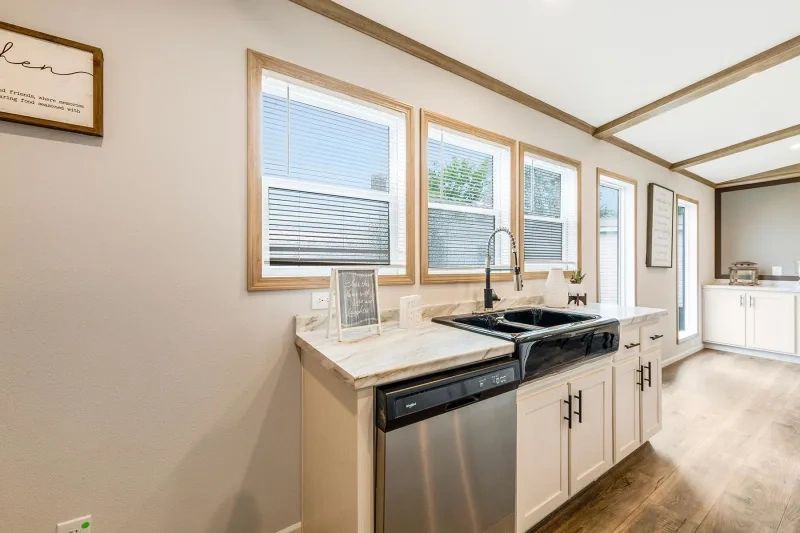 A kitchen with a sink , dishwasher , and lots of windows.