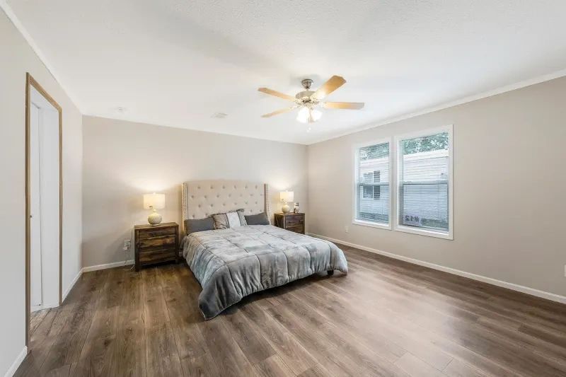 A bedroom with a bed , nightstands , and a ceiling fan.