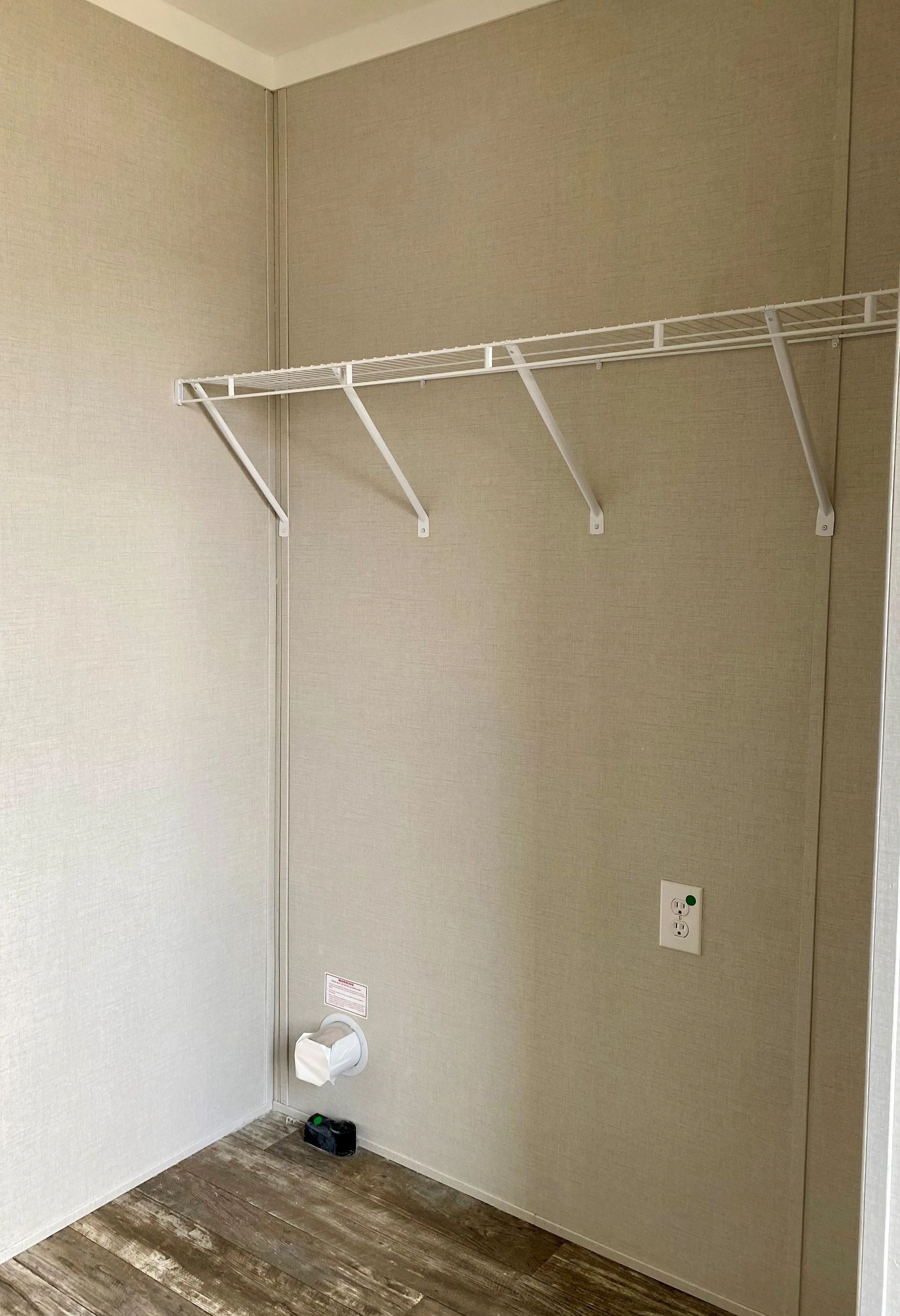 A walk in closet in a mobile home with shelves and a wooden floor.