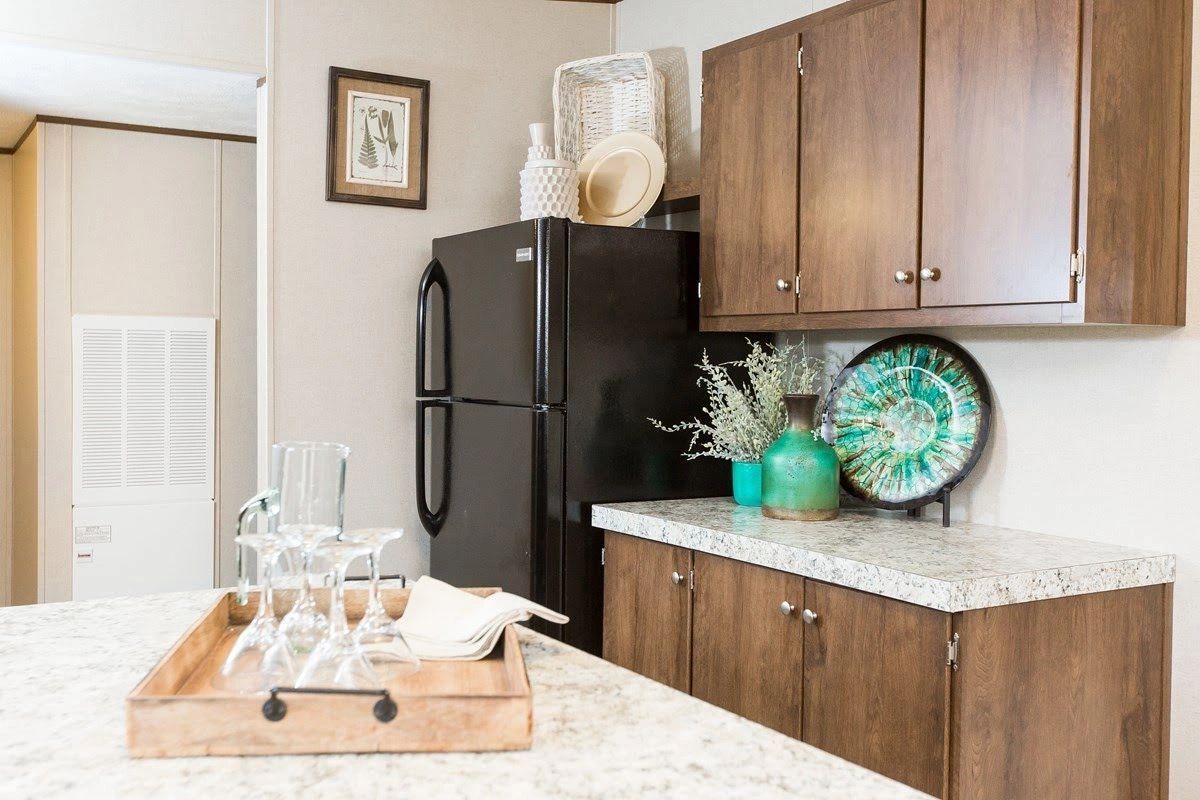 A kitchen with a black refrigerator and wooden cabinets.