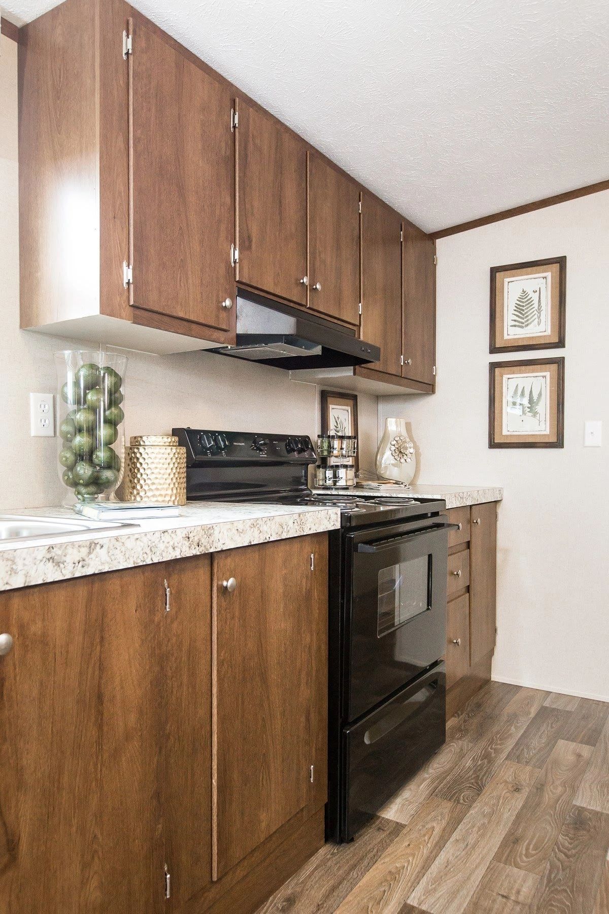 A kitchen with wooden cabinets , a stove , and a sink.