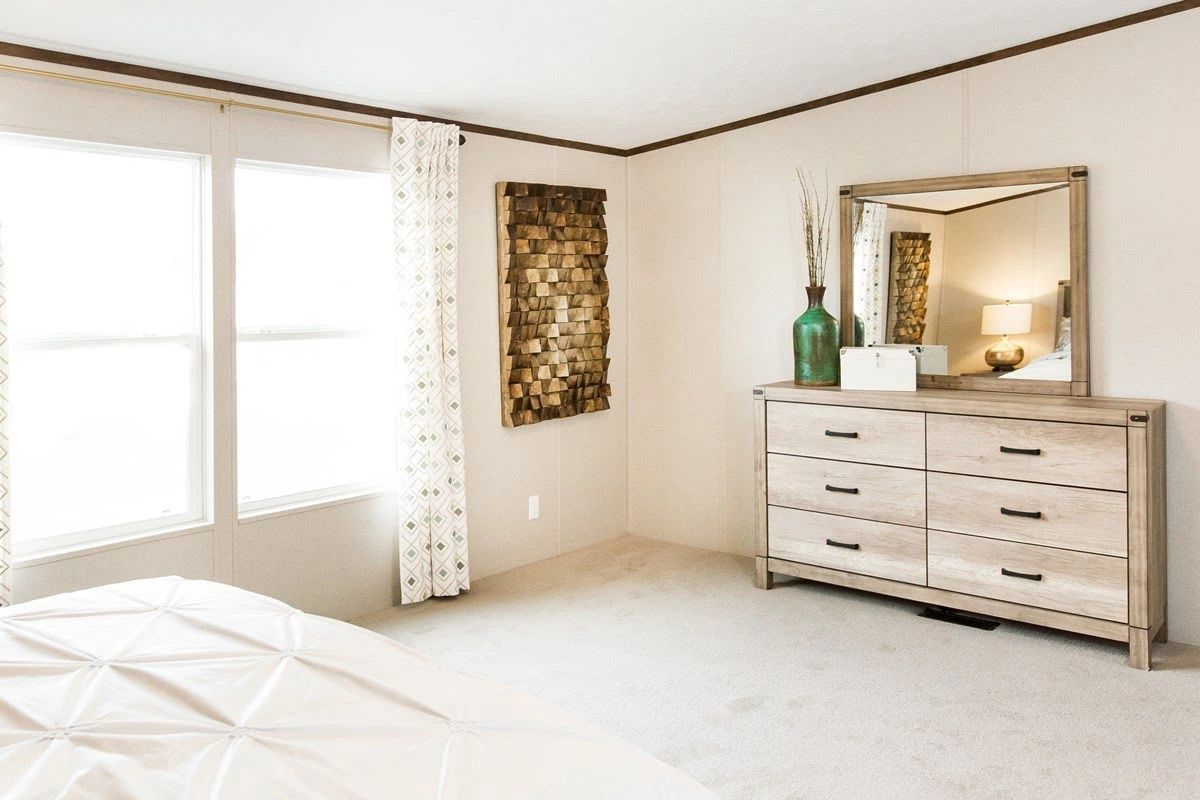 A bedroom with a bed , dresser and mirror.