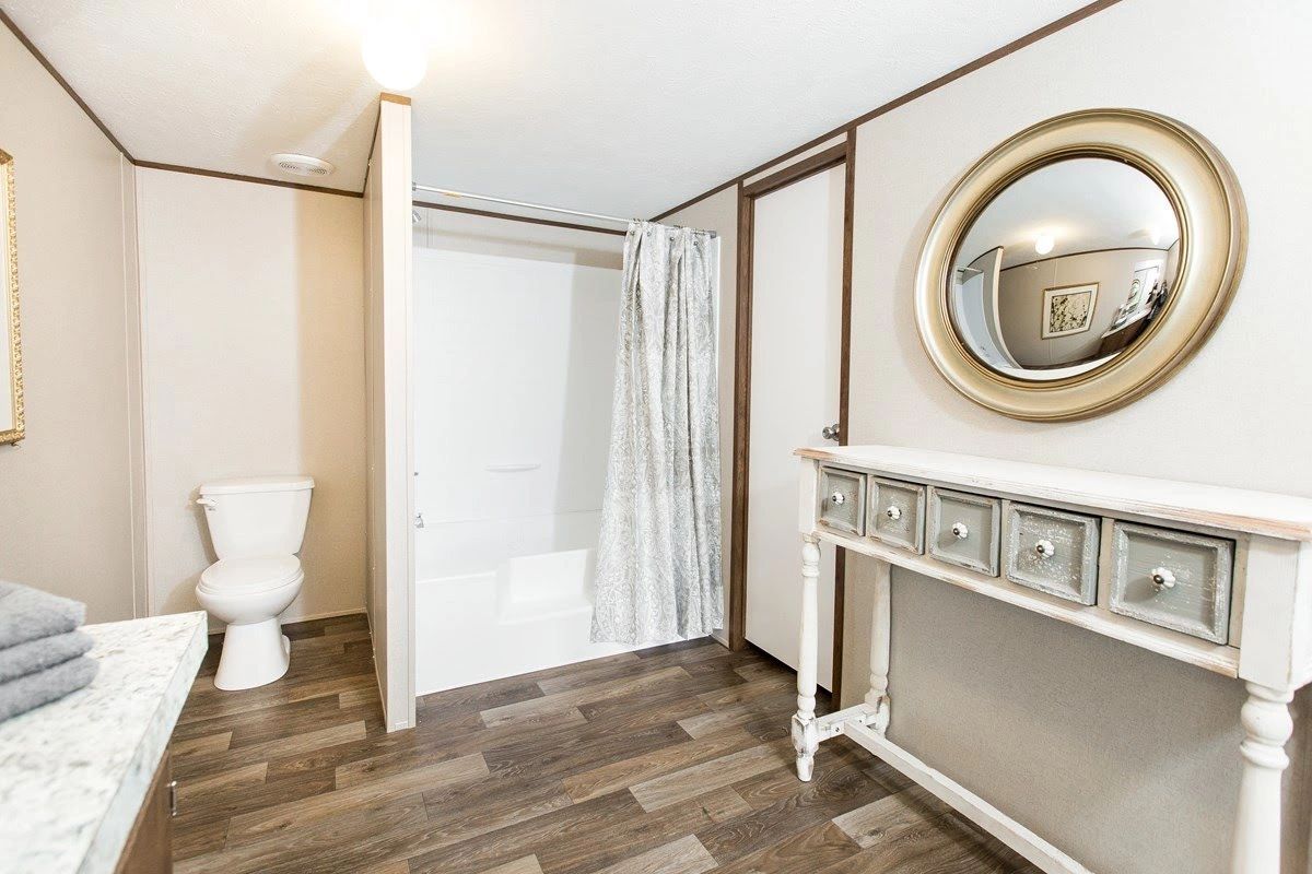A bathroom with a toilet , sink , shower and mirror.