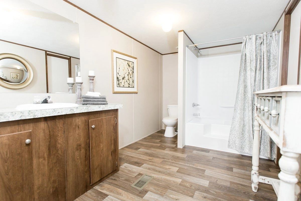 A bathroom with a sink , toilet , shower and mirror.
