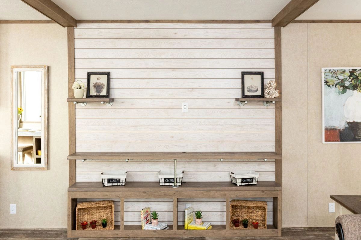 A living room with a wall mounted entertainment center and shelves.