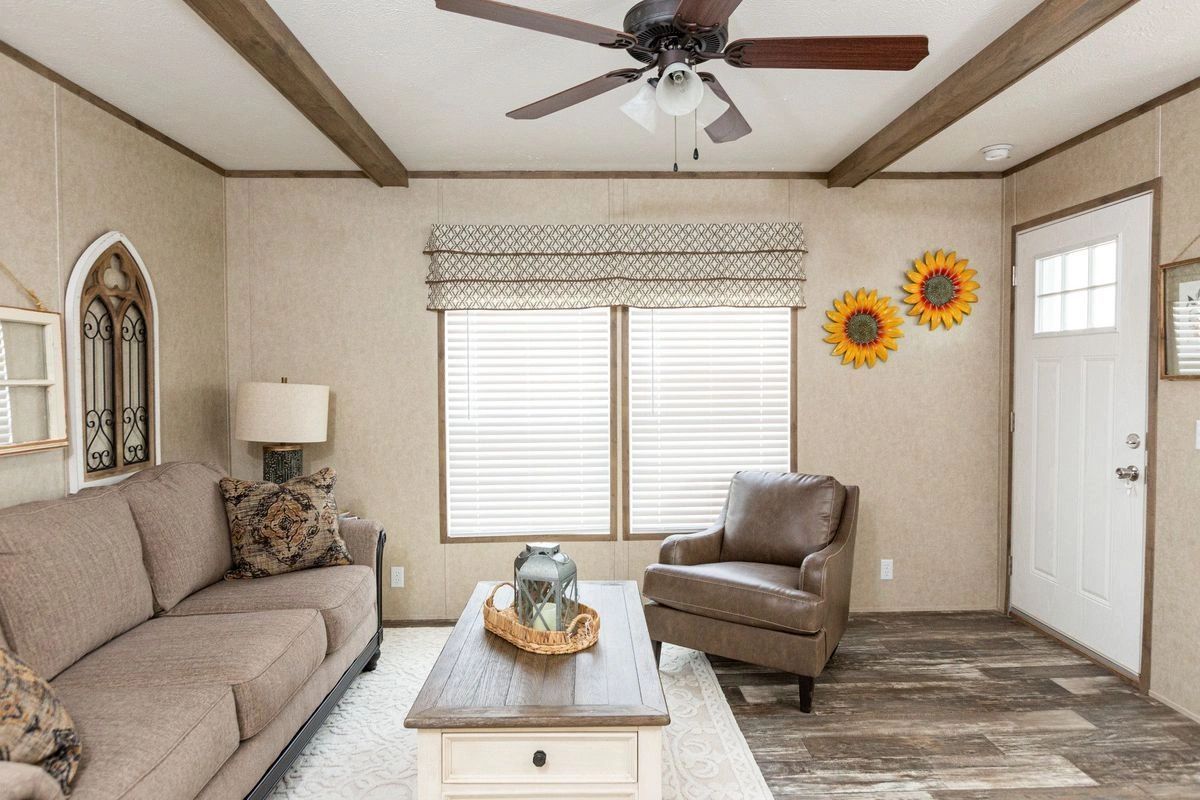 A living room with a couch , chair , coffee table and ceiling fan.