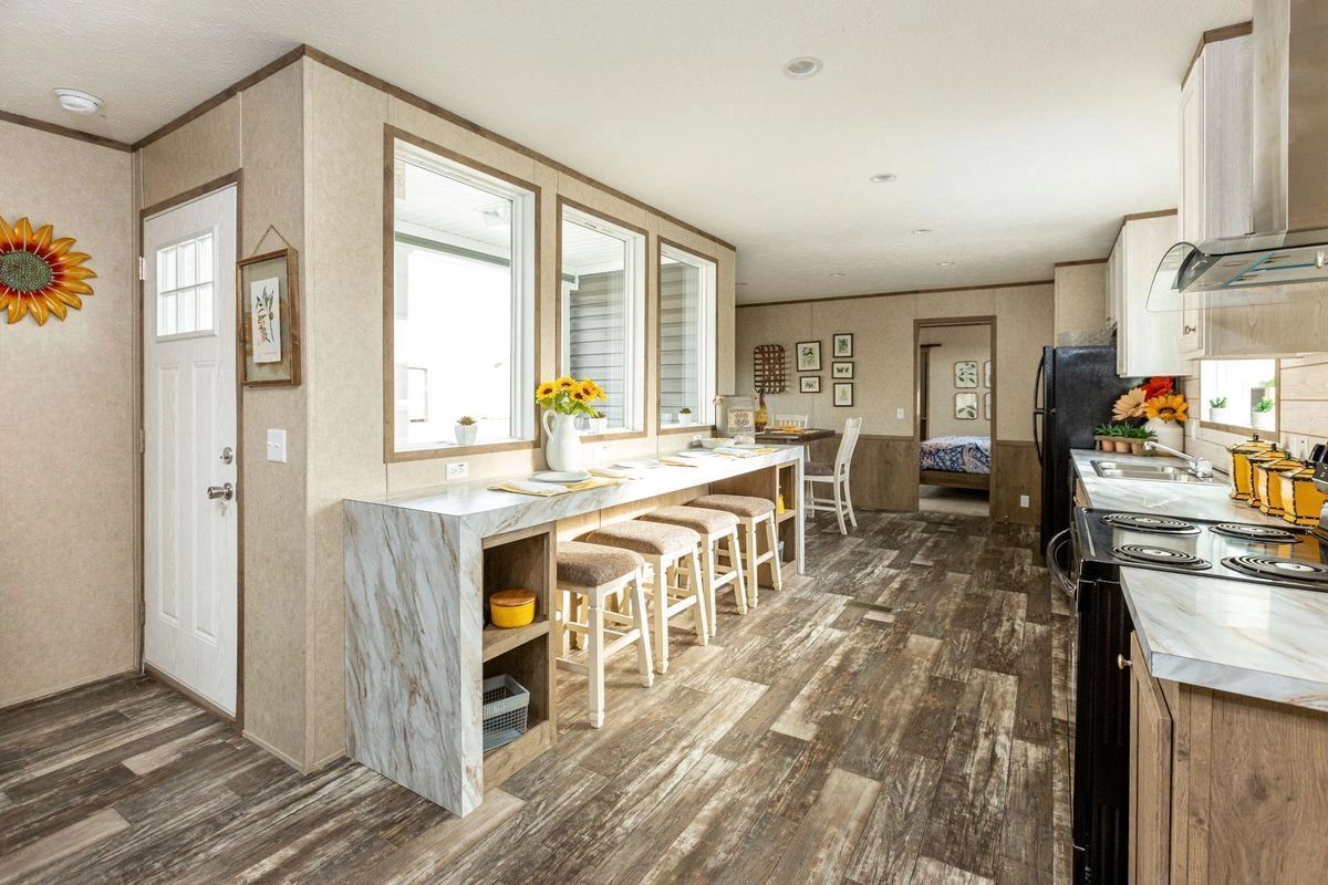A kitchen in a mobile home with a long counter and stools.