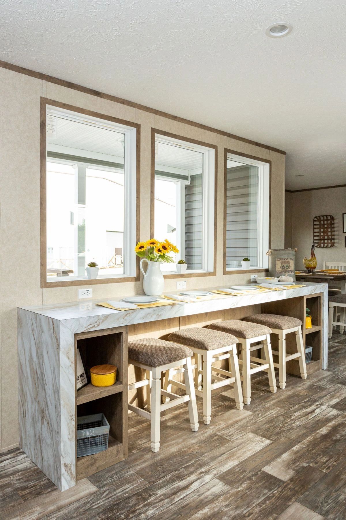 A kitchen with a long table and stools and three mirrors.