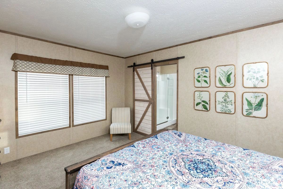 A bedroom with a bed , chair , and sliding barn doors.