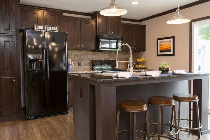 A kitchen with a black refrigerator , sink , and stools.