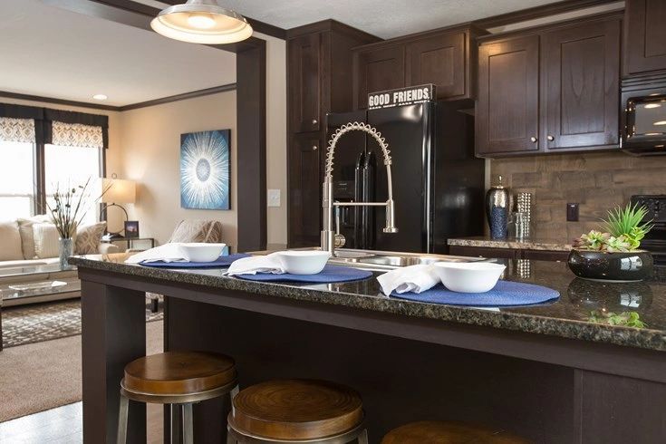 A kitchen with a sink , refrigerator , microwave and stools.