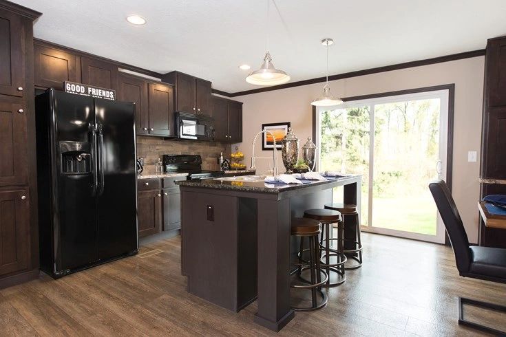 A kitchen with a large island and a black refrigerator.