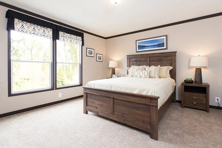 A bedroom with a king size bed and two windows.