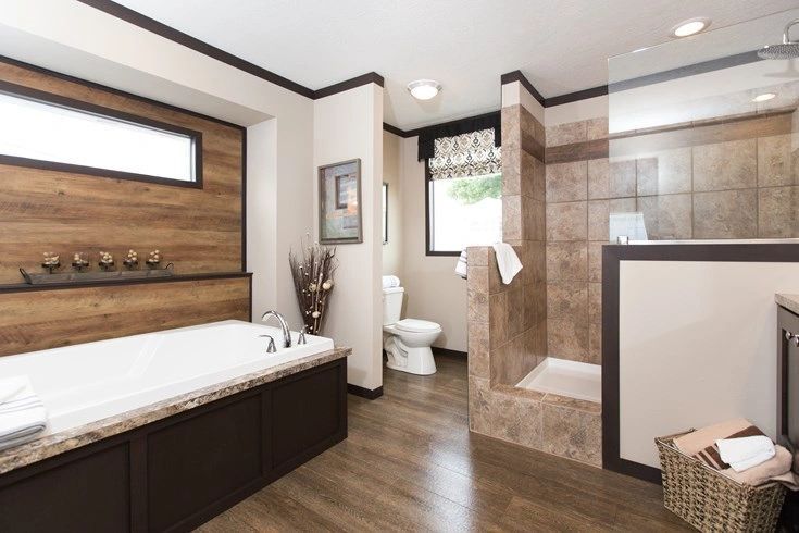 A bathroom with a tub , toilet , shower and window.