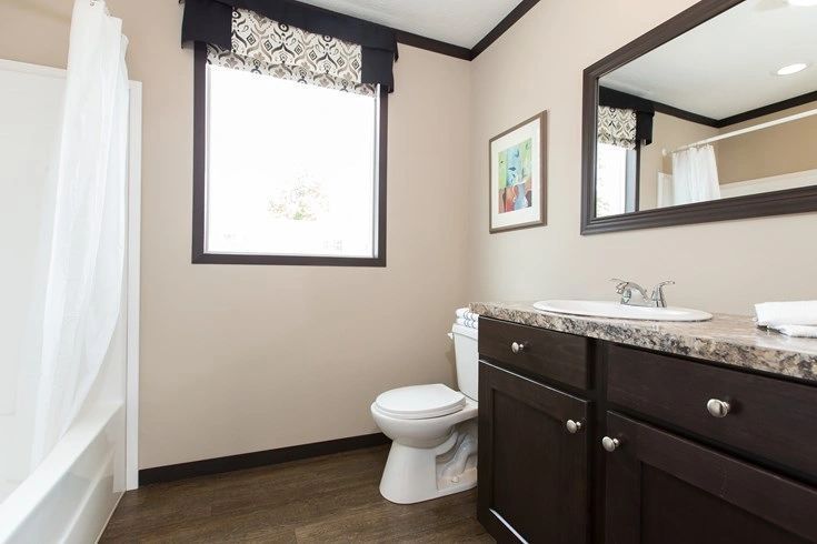 A bathroom with a toilet , sink , and mirror.