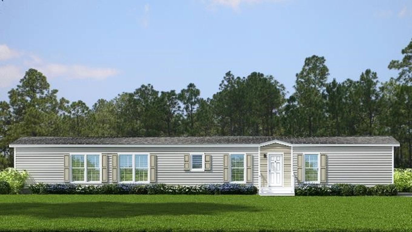 A large mobile home is sitting on top of a lush green field.