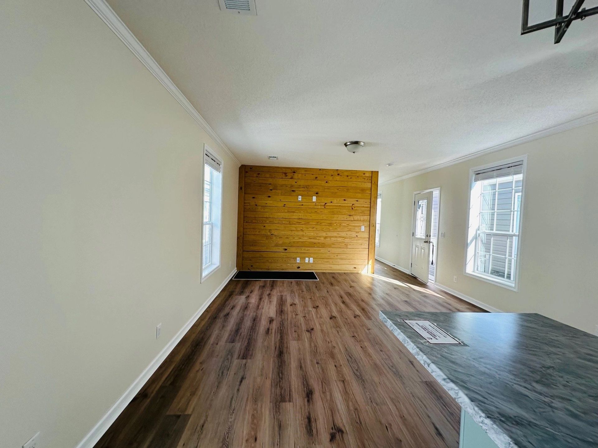 An empty living room with hardwood floors and a wooden wall.