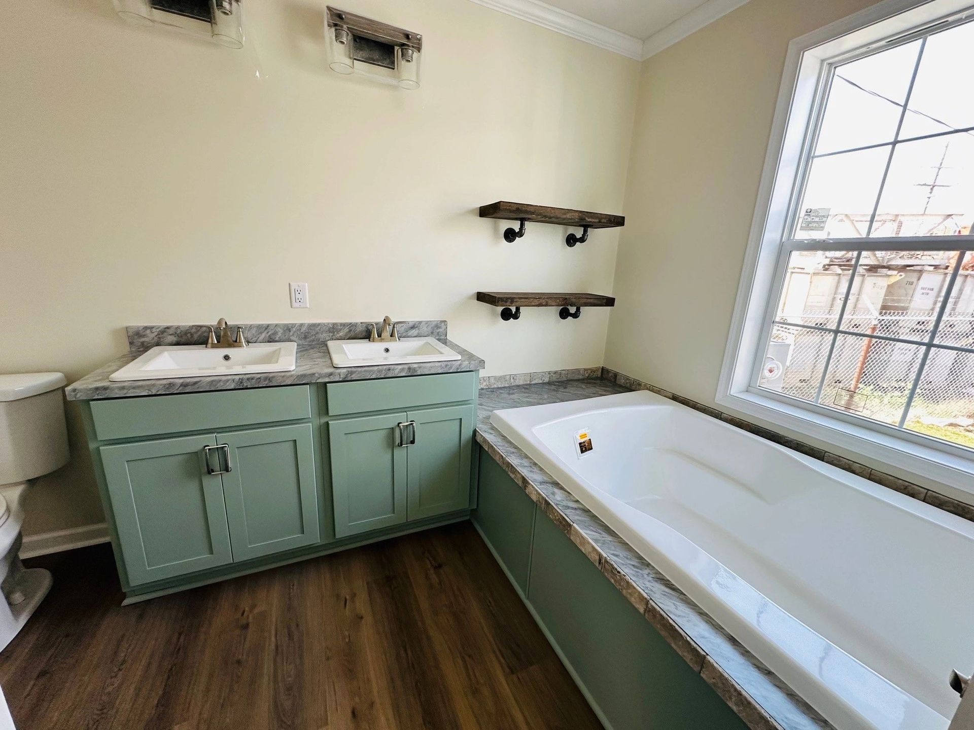 A bathroom with two sinks , a tub and a window.