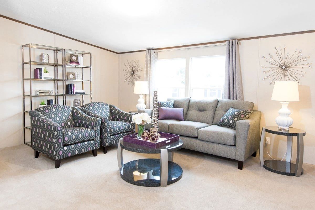 A living room with a couch , two chairs , a coffee table and a bookshelf.