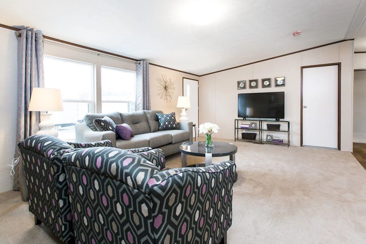 A living room with a couch , chairs , and a flat screen tv.