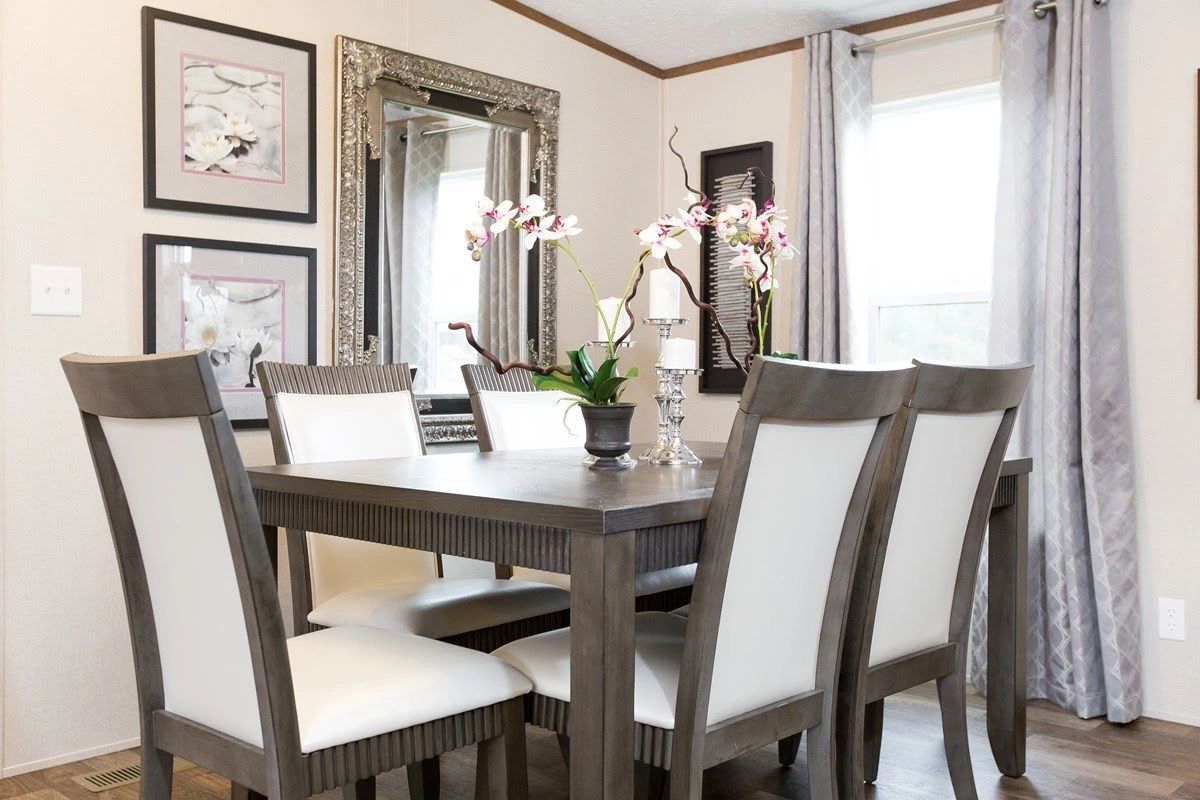 A dining room with a table and chairs and a mirror.