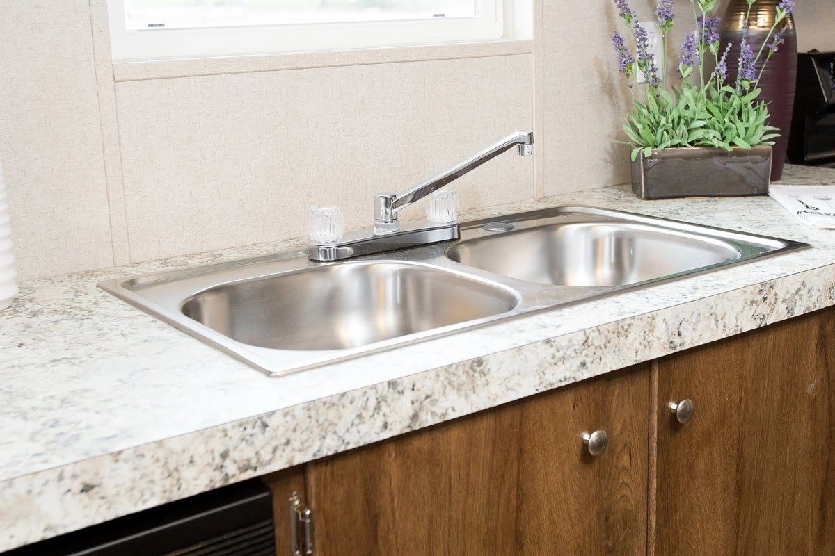 A kitchen with a stainless steel sink and a granite counter top.