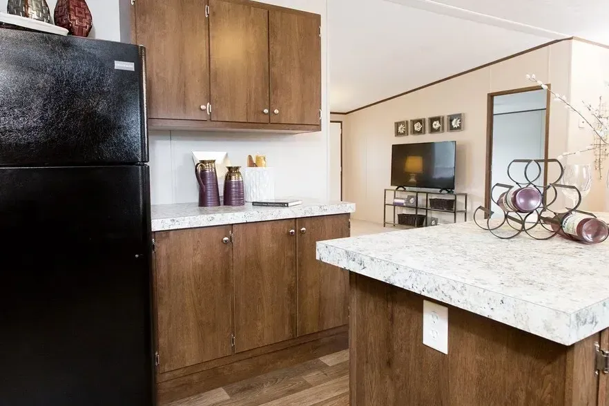 A kitchen with a black refrigerator , wooden cabinets , and a white counter top.