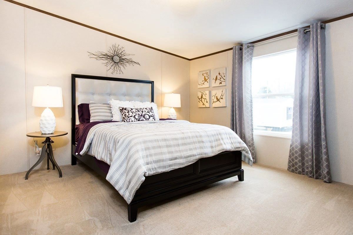 A bedroom with a large bed , two lamps , and a window.