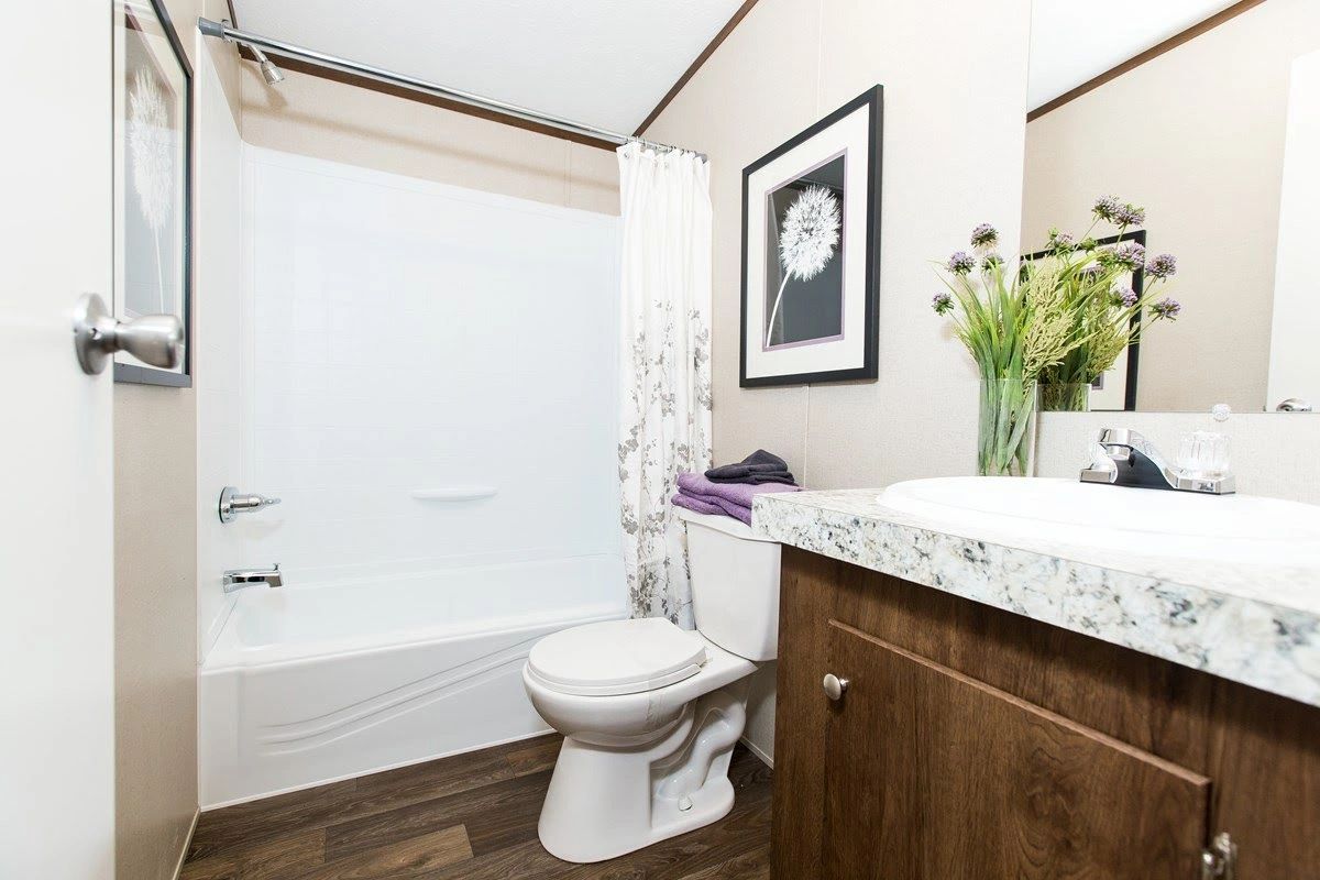 A bathroom with a toilet , sink , tub and mirror.