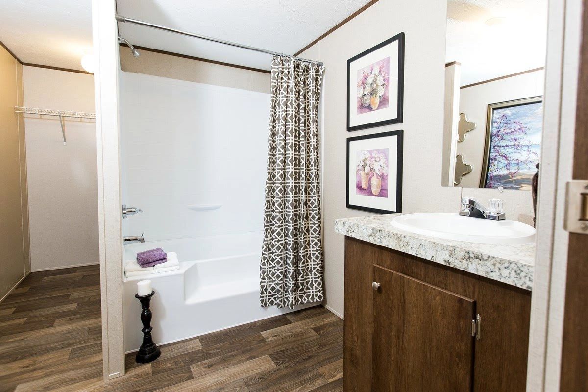 A bathroom with a sink , tub , shower and mirror.