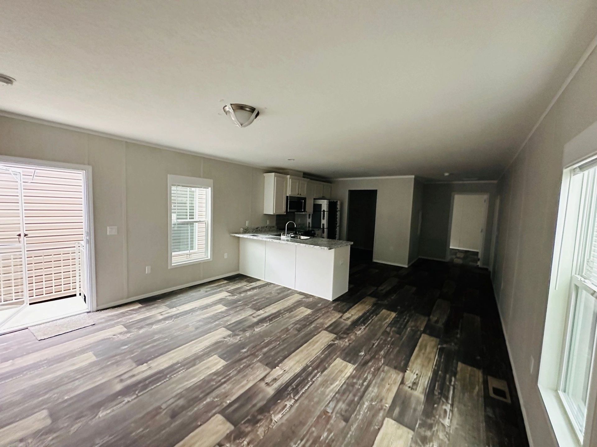 A living room with hardwood floors and a kitchen in a mobile home.
