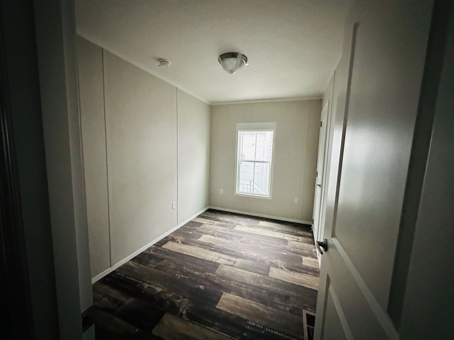 An empty room with a wooden floor and a window.