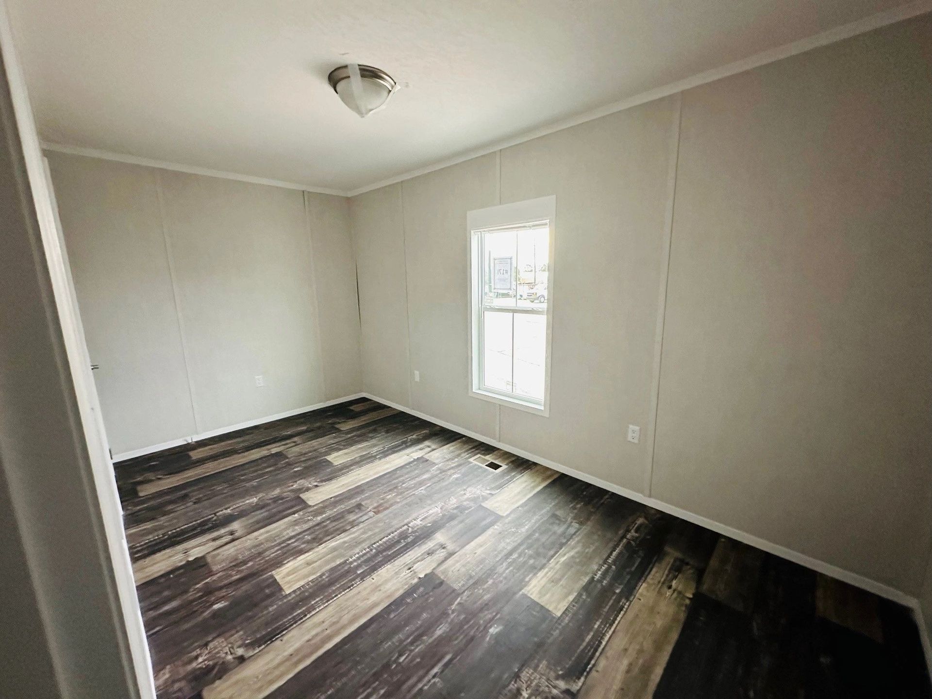 An empty room with a wooden floor and a window.