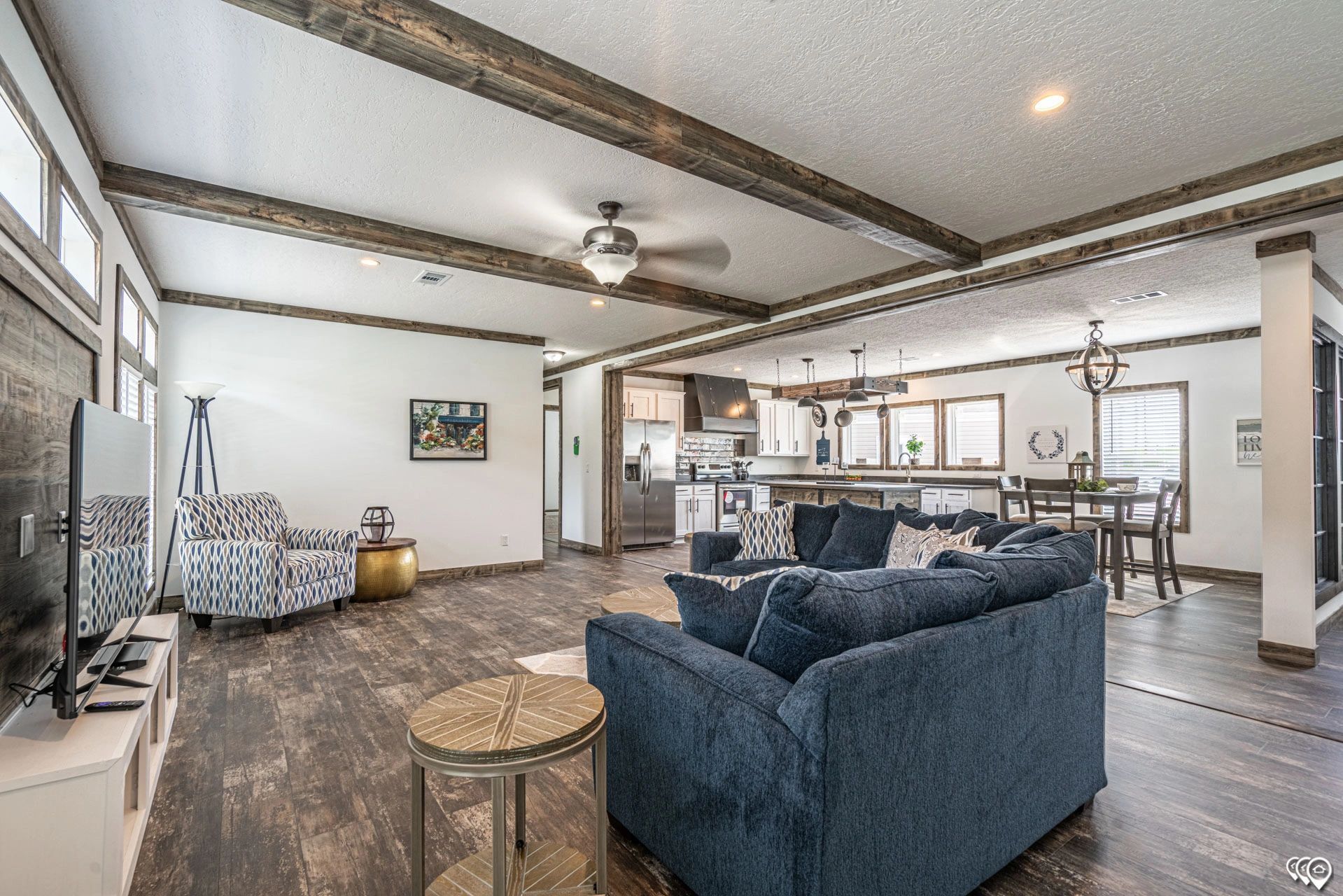 A living room with a blue couch , chairs , a television and a ceiling fan.