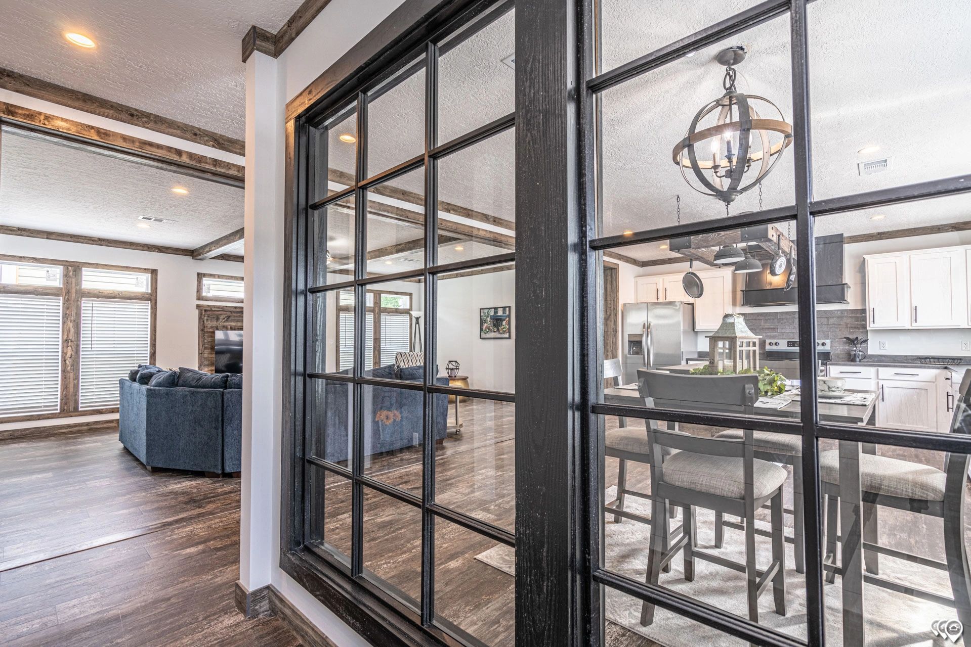 A living room with a lot of windows and a dining room in the background.