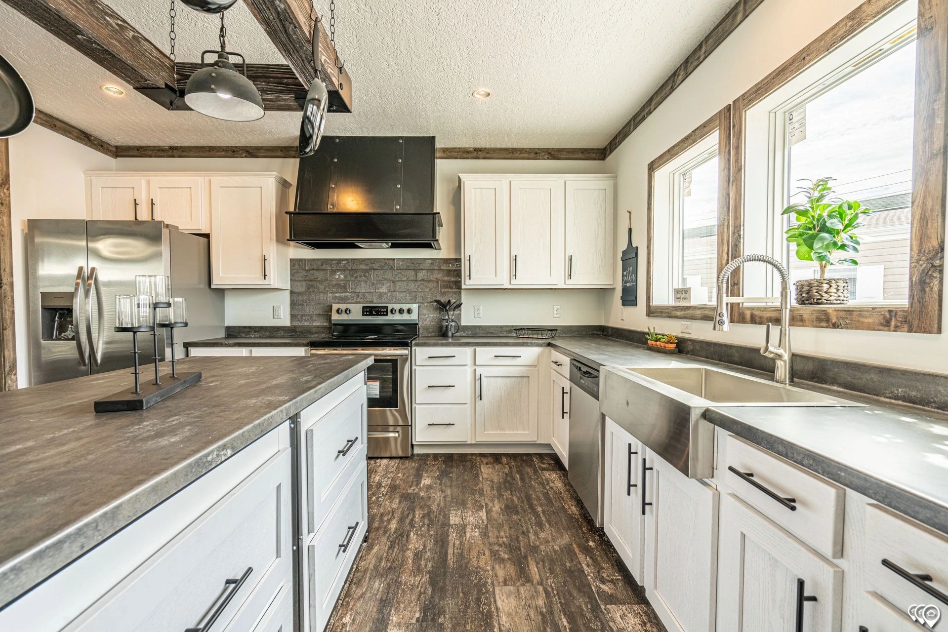 A kitchen with white cabinets , stainless steel appliances , a sink and a refrigerator.