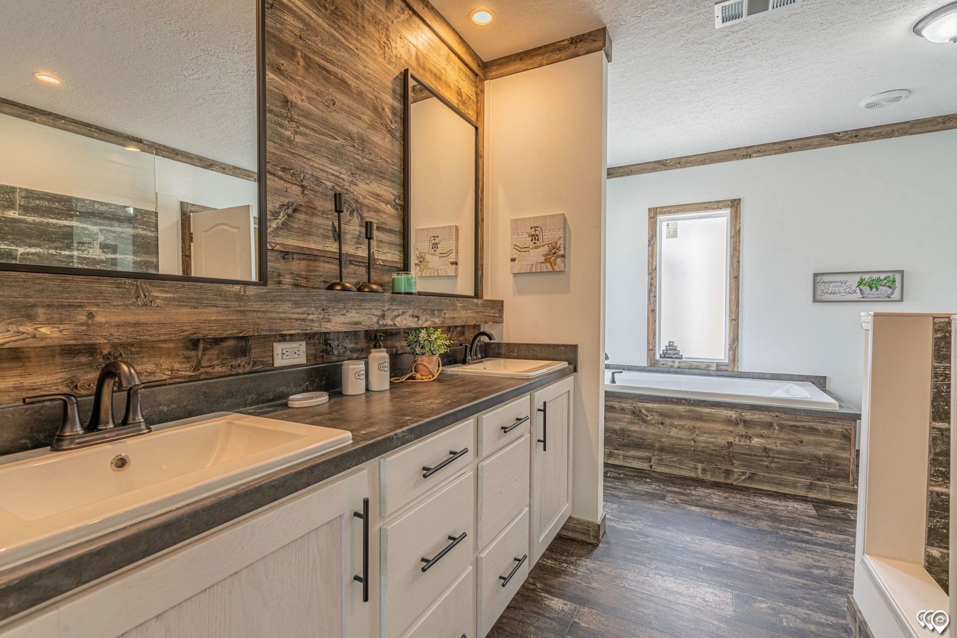 A bathroom with two sinks , a tub and two mirrors.