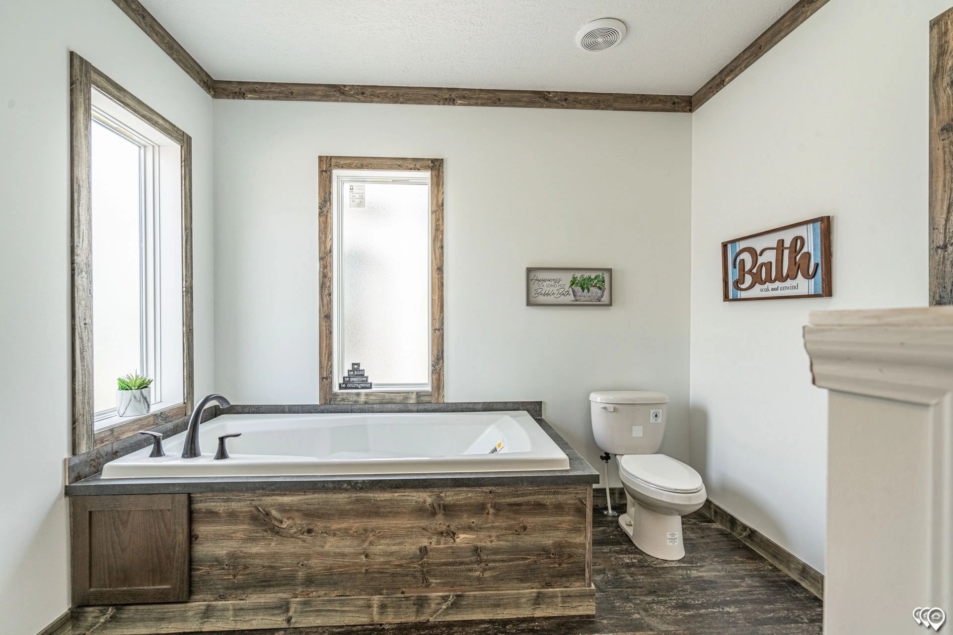 A bathroom with a tub , toilet , and window.