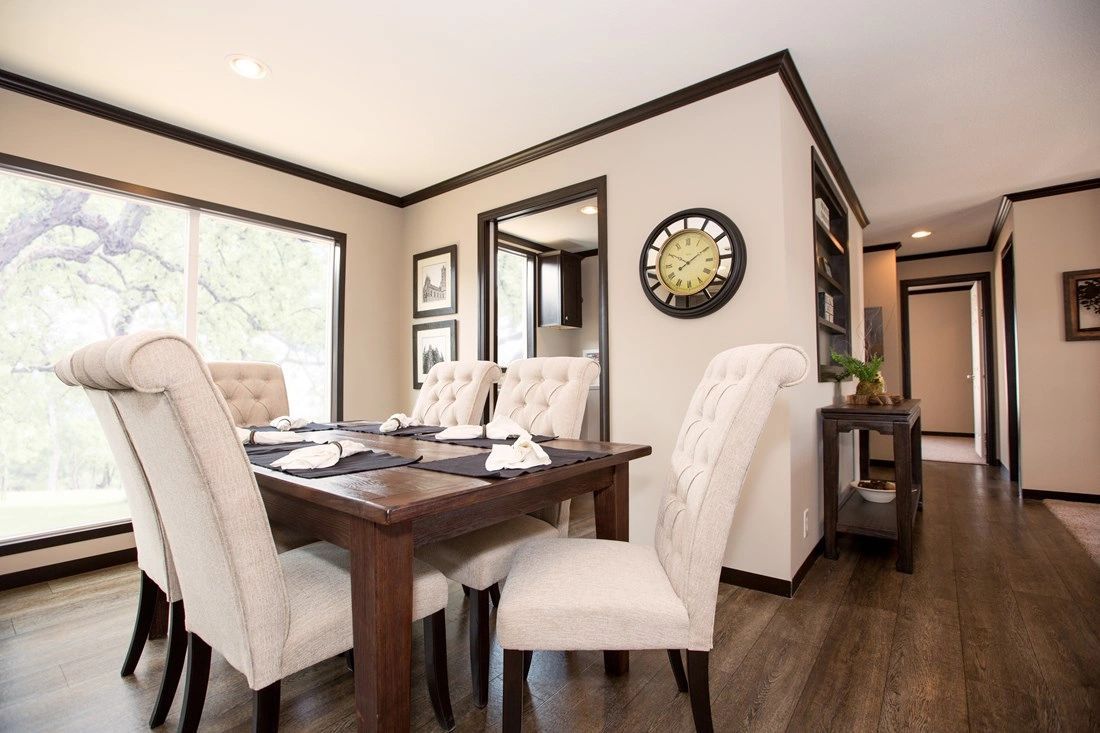A dining room with a table and chairs and a clock on the wall.